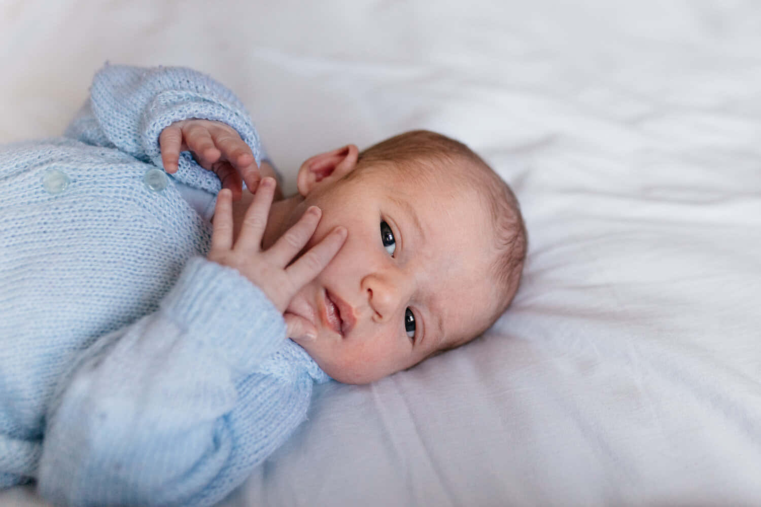 Enbaby Boy Ligger På En Säng Med Sina Händer På Ansiktet