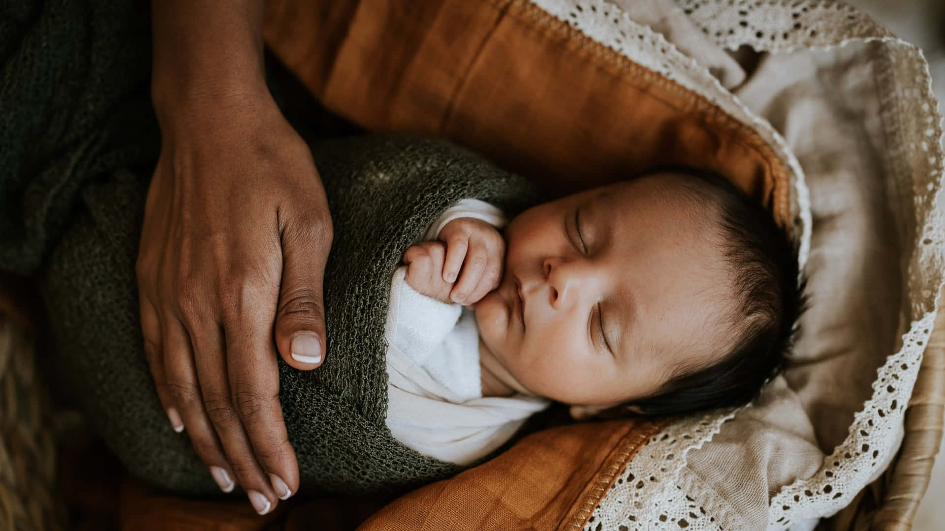 A newborn baby peacefully sleeping in a comfy blanket wrap
