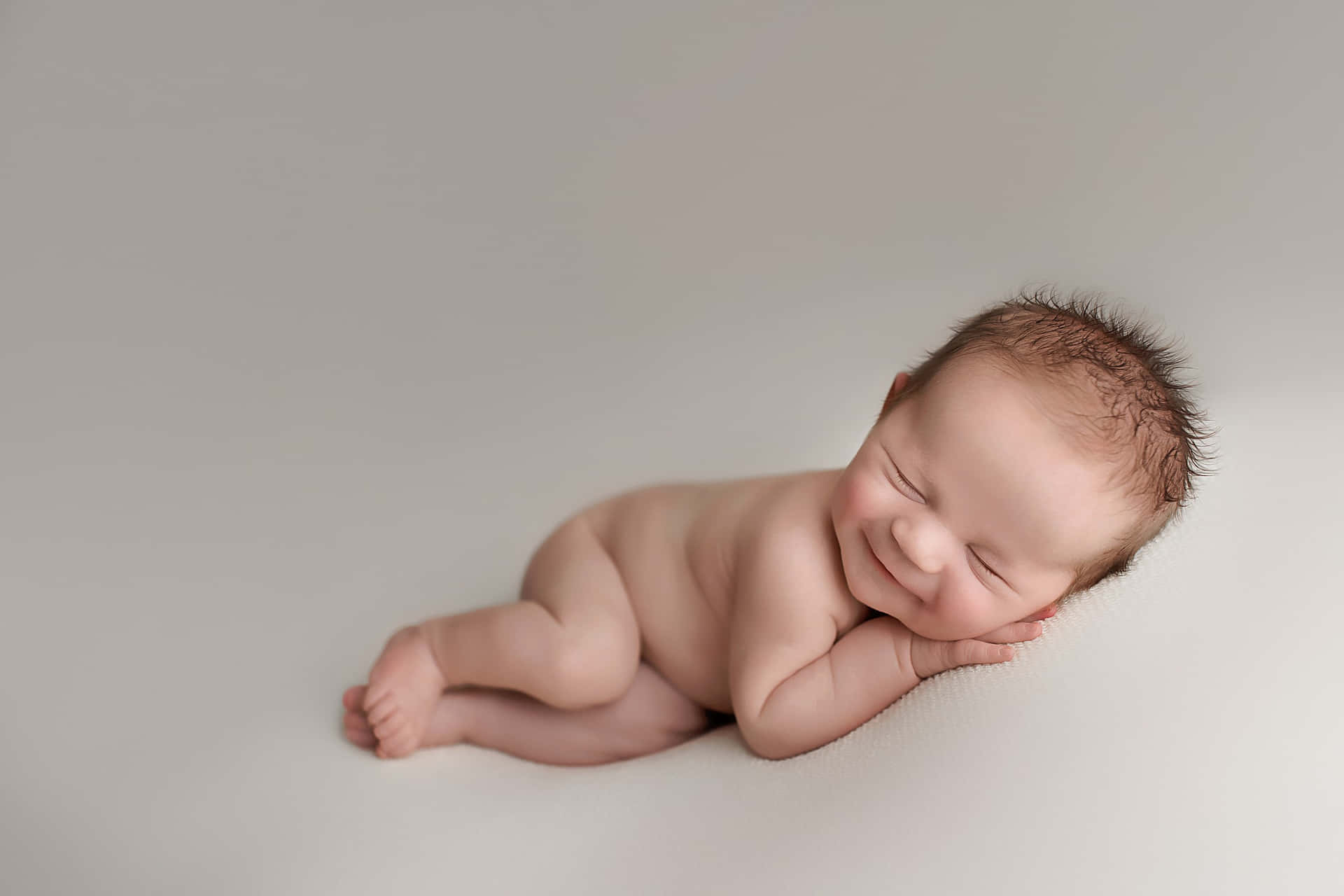 A Baby Boy Is Laying On A Gray Background