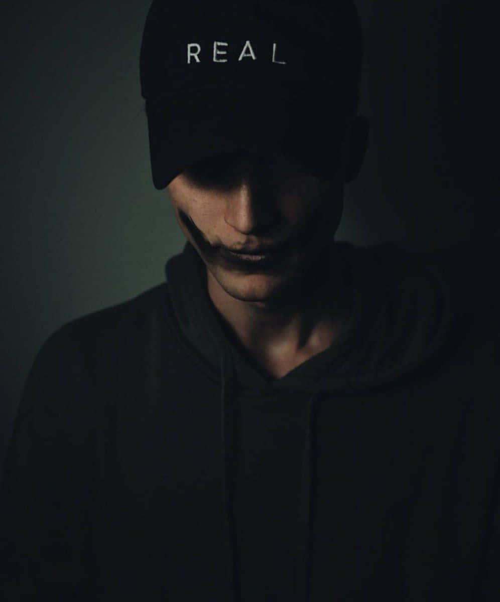 A Man Wearing A Black Baseball Cap With The Word Real On It Wallpaper