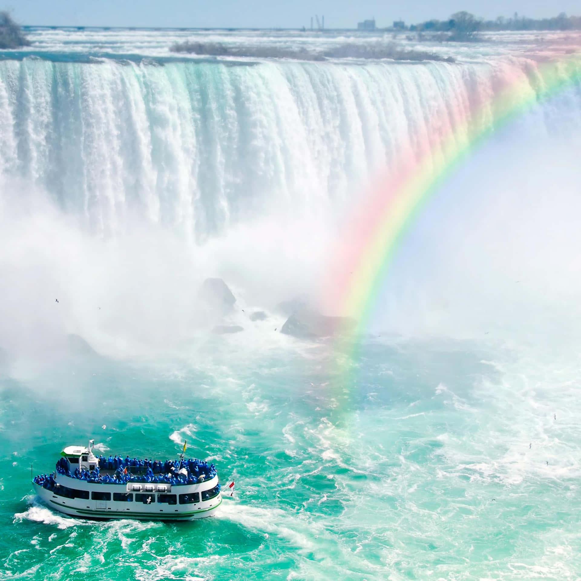 A Boat Is Traveling In Front Of Niagara Falls With A Rainbow