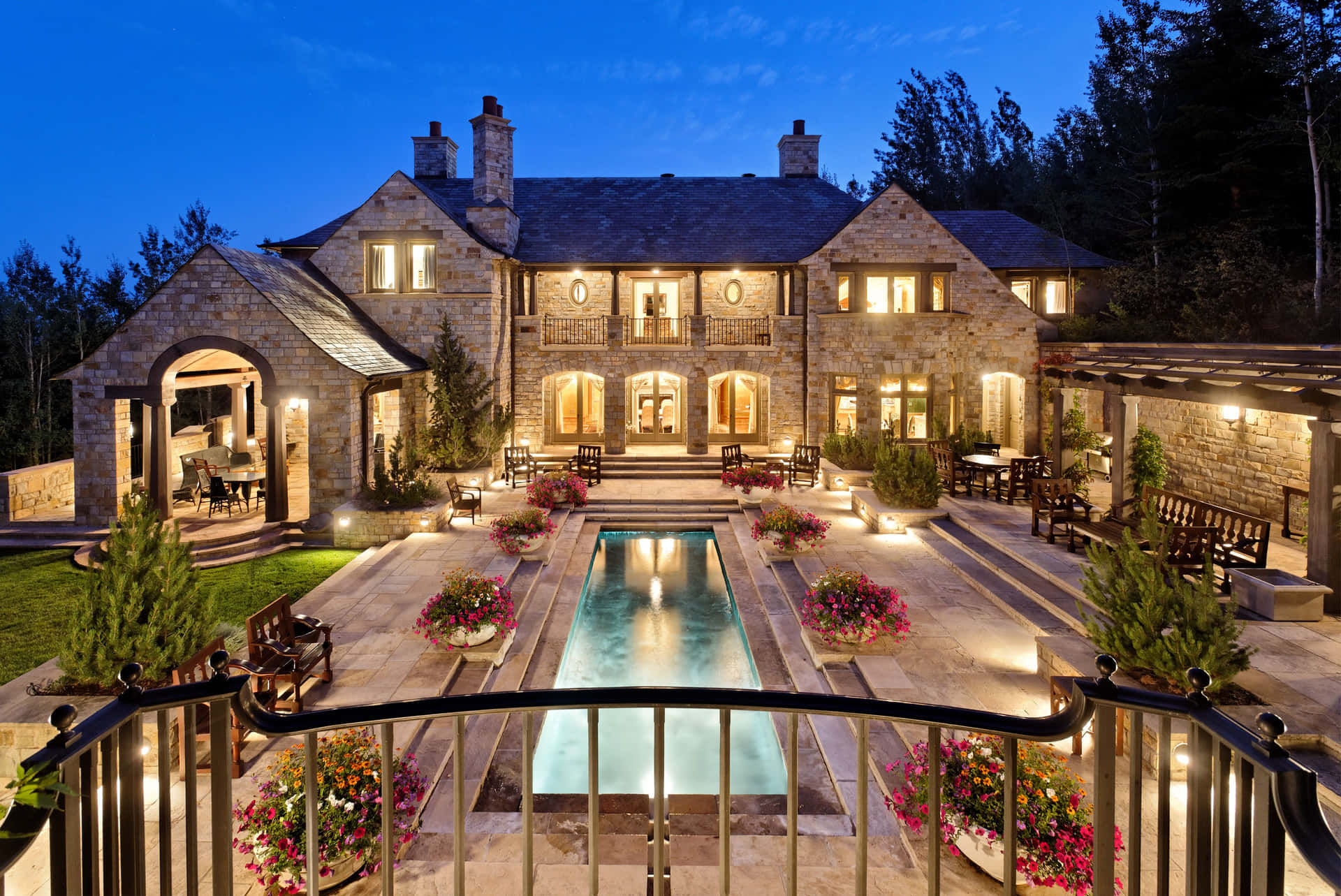 A Large Stone House With A Pool And Patio