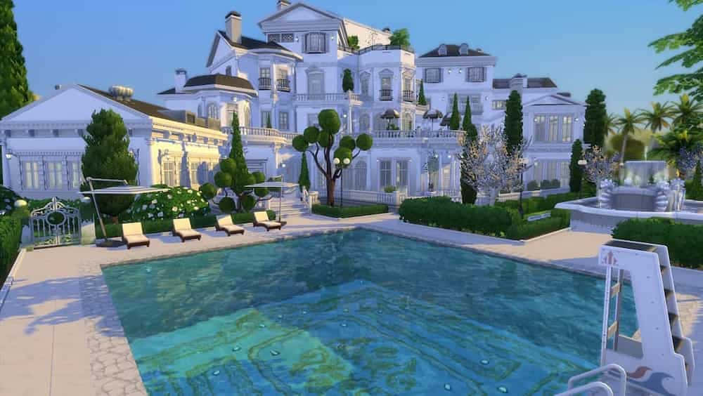 A Large White House With A Pool And Lounge Chairs