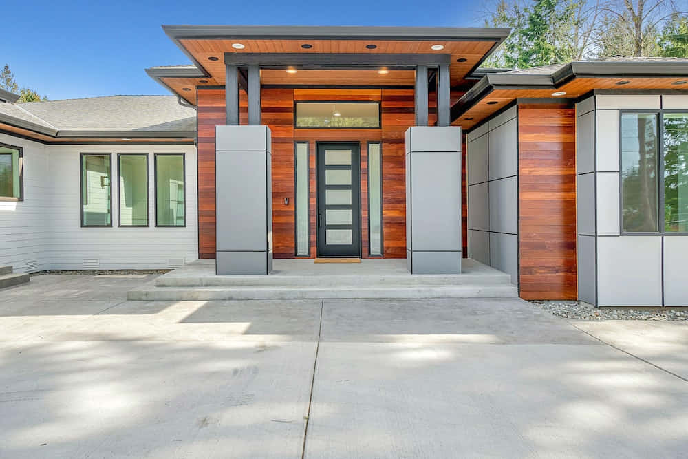 A Modern Home With A Wooden Door And A Large Driveway