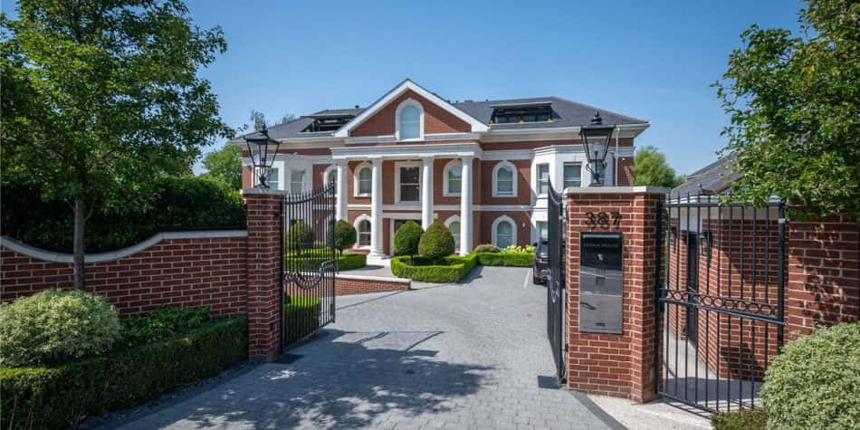 A Large Brick House With A Gated Entrance