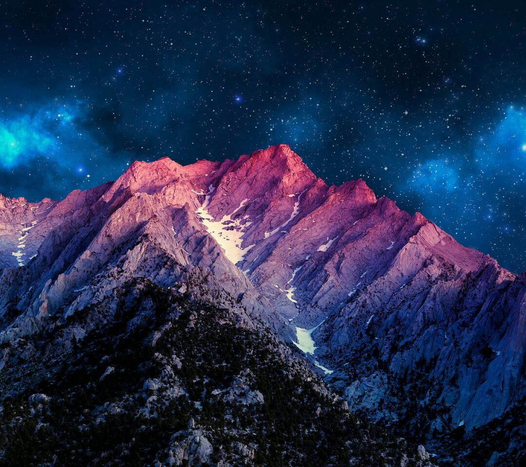 A Mountain Range With Stars And A Galaxy In The Background Wallpaper