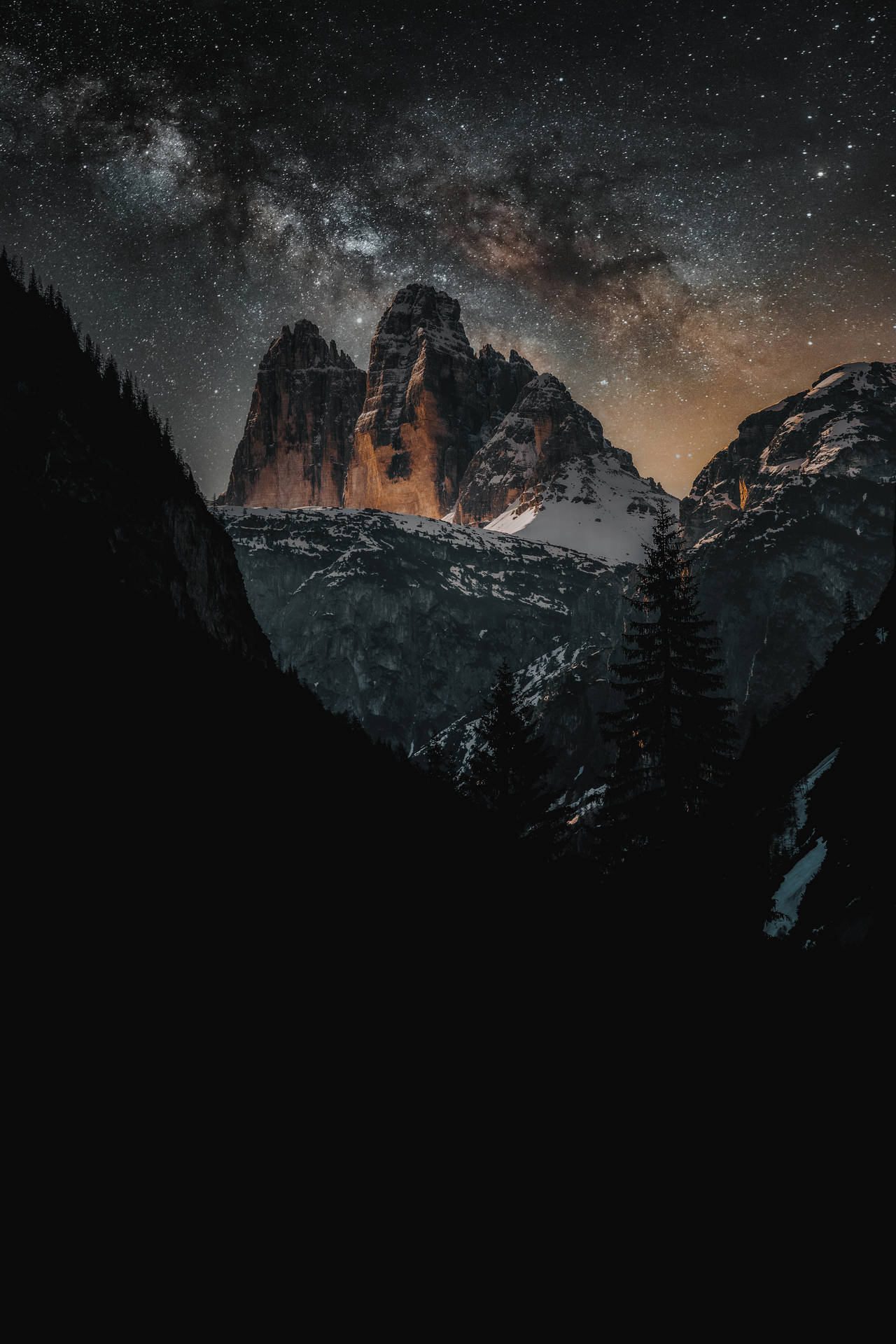 A majestic view of the night sky over a snow-capped mountain Wallpaper