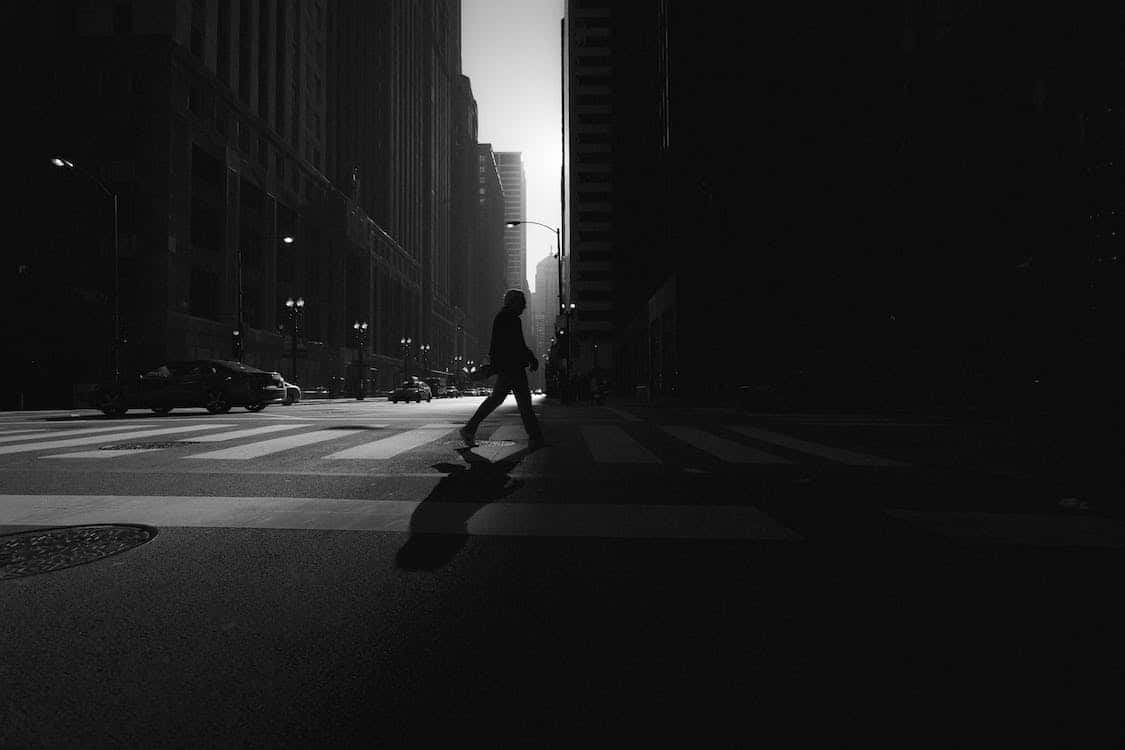 A Person Is Crossing A Street In The Dark