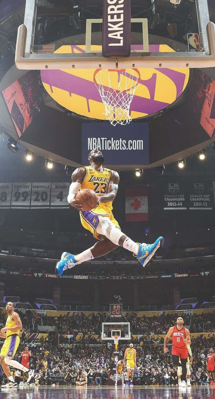 A Basketball Player Is In Mid Air While Dunking A Basketball Wallpaper