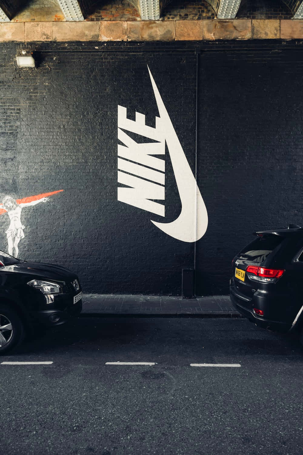 En sort bil parkeret foran en Nike væg