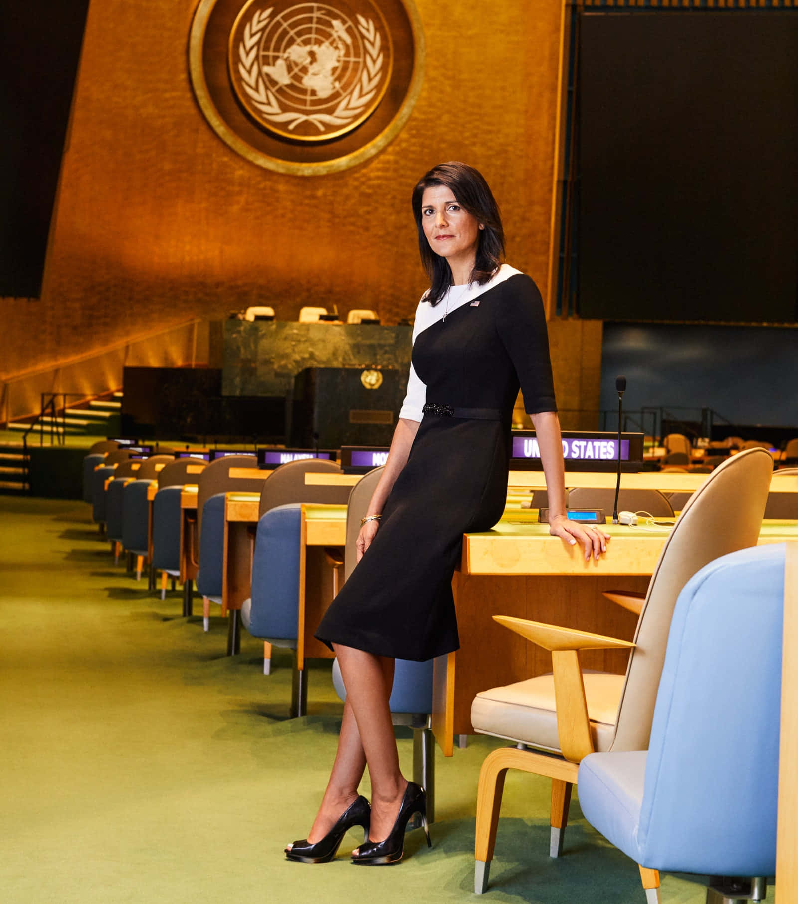 Nikki Haley confidently posing beside a table in a stylish outfit. Wallpaper