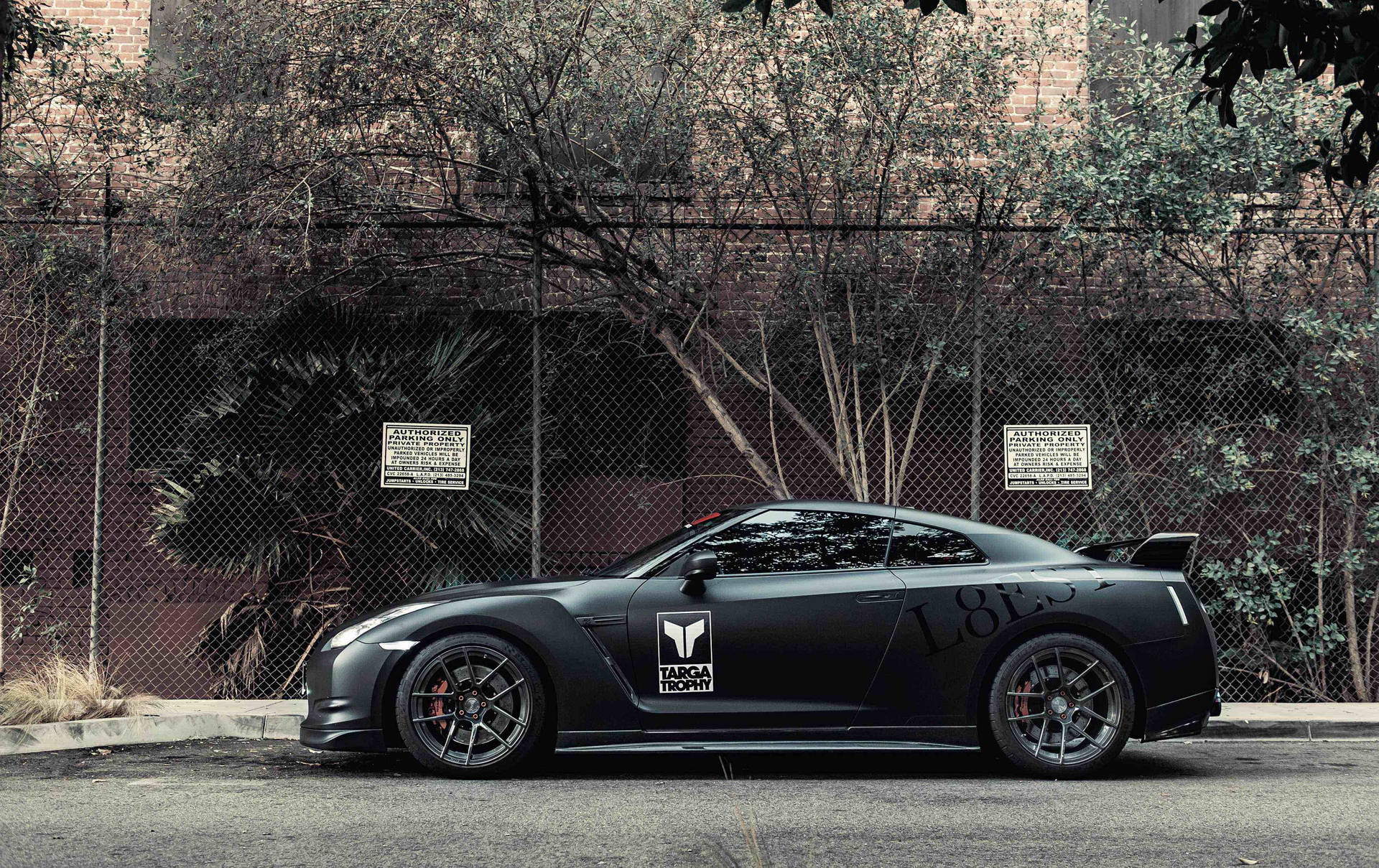 Caption: Powerful Nissan Skyline GTR R35 parked behind mesh fencing. Wallpaper