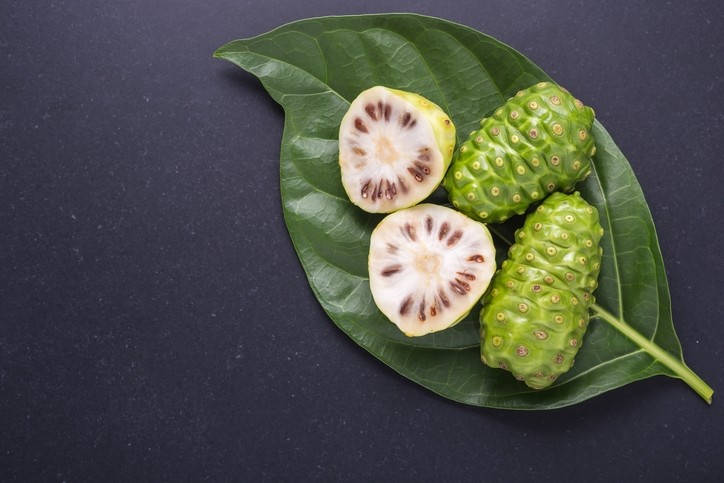 Vibrant Noni Fruits Nestled in Lush Green Foilage Wallpaper