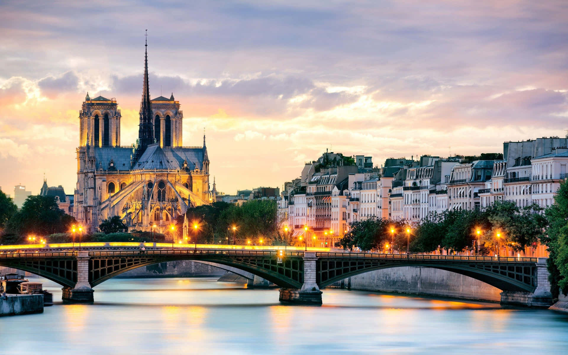 Notre Dame Cathedral With Bridge Lit With Orange Lights Wallpaper