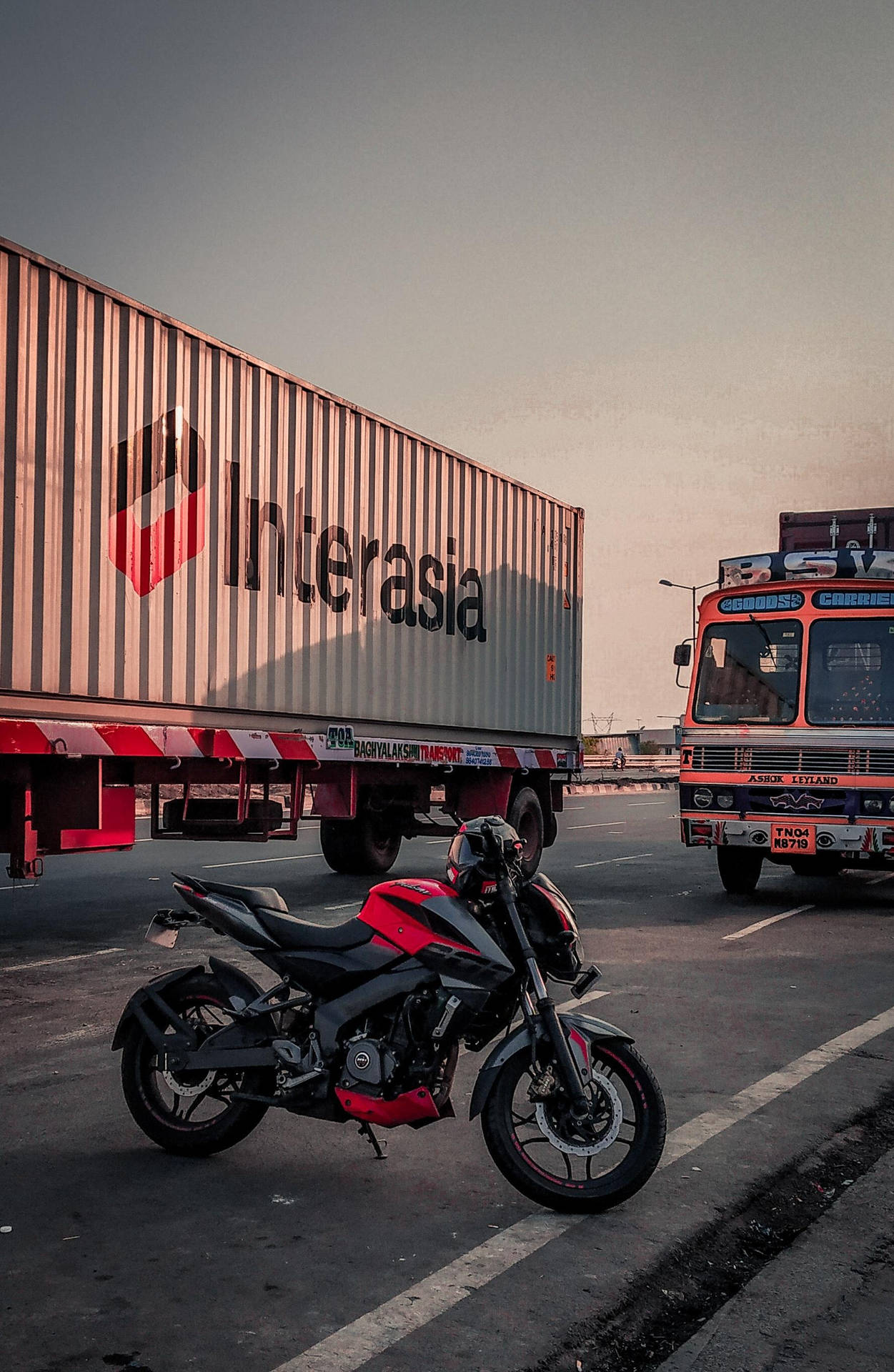NS 200 sort og rød motorcykel nær Lastbil Tapet Wallpaper