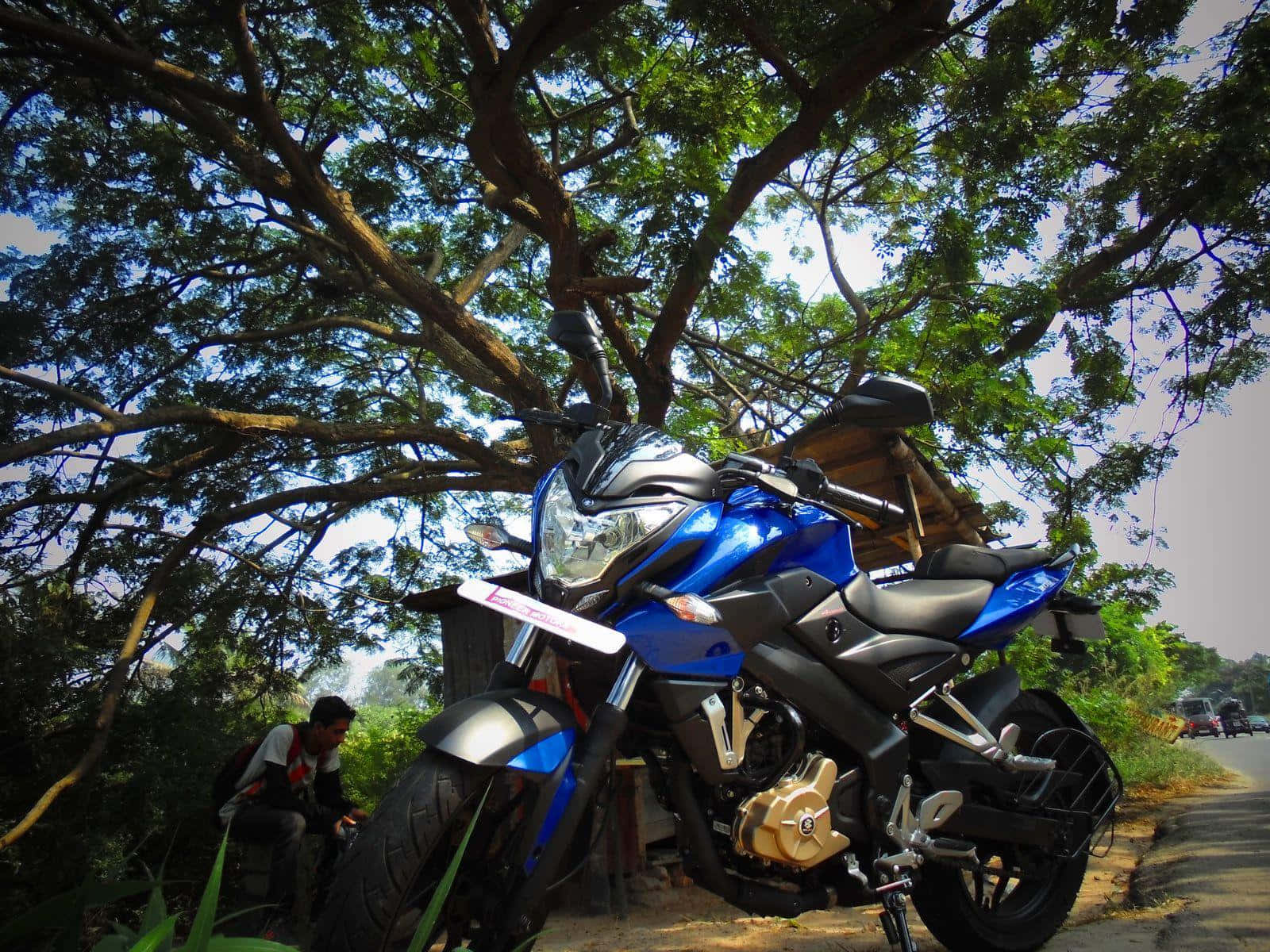 A Blue Motorcycle Parked On A Road Next To A Tree