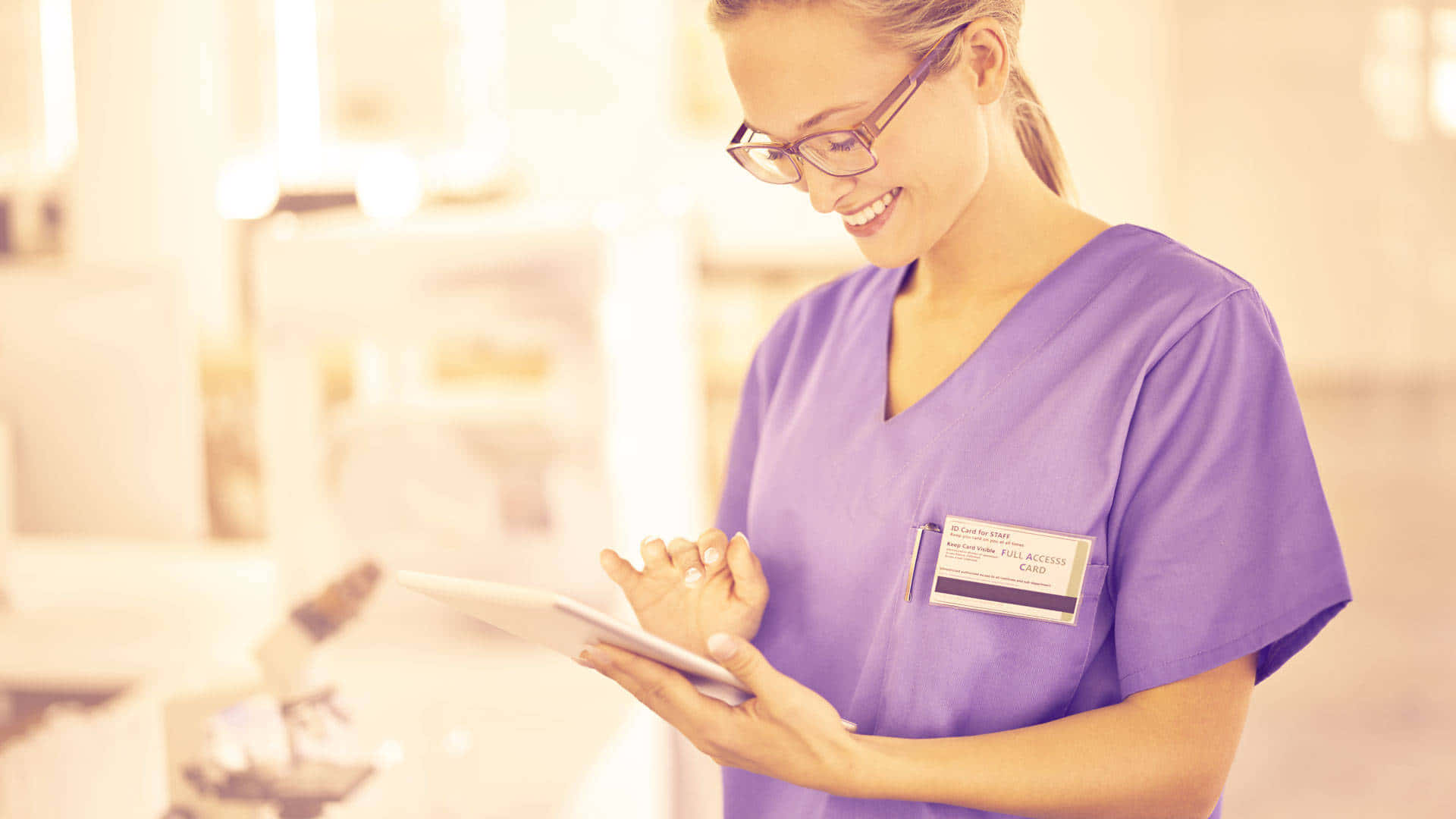 A Nurse Wearing Purple Scrubs Holding A Tablet