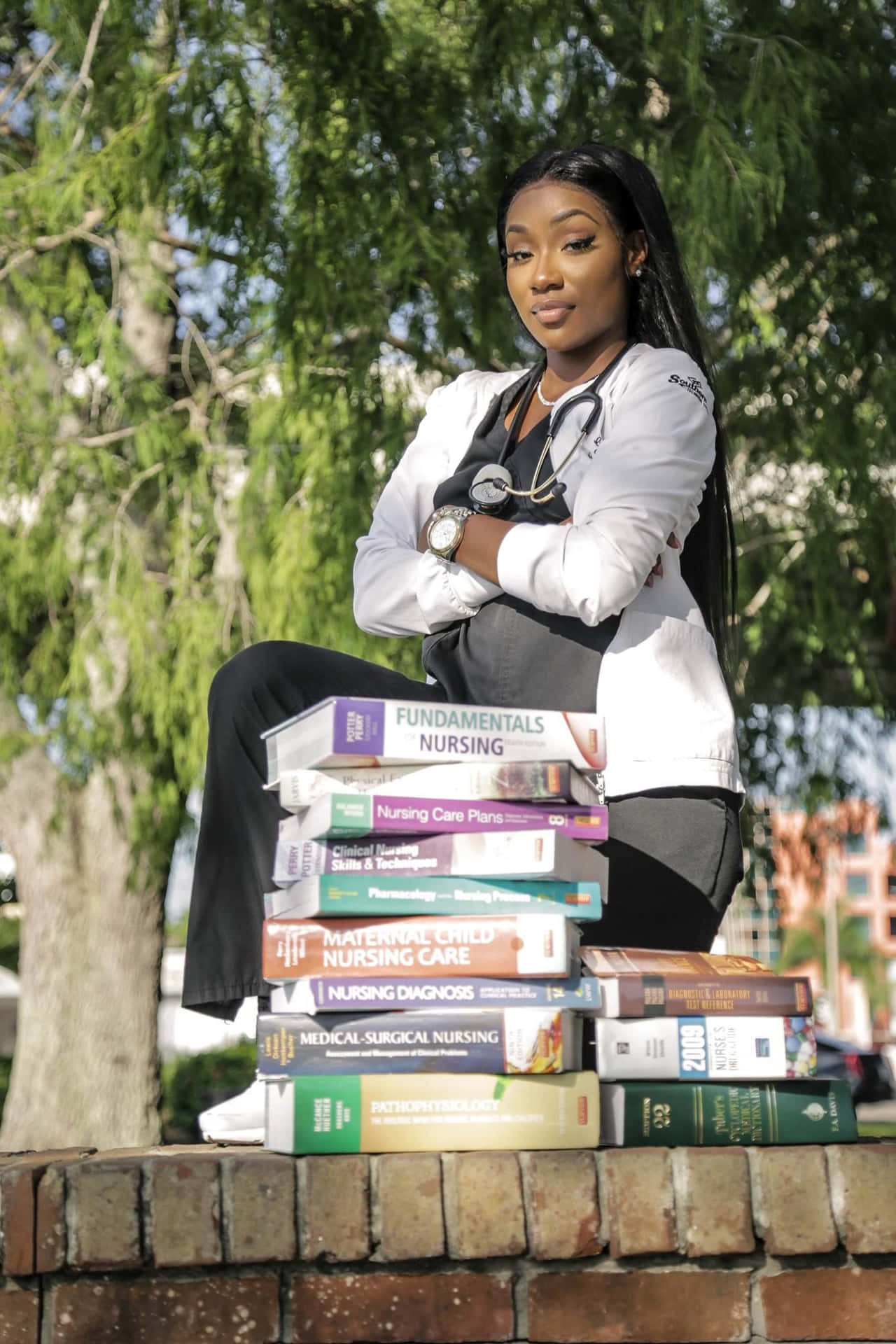 A Woman Sitting On A Brick Wall With A Stack Of Books