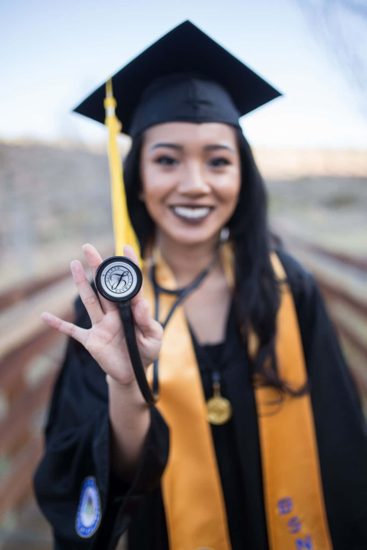 A Young Woman In A Graduation Gown Holding A Stethoscope