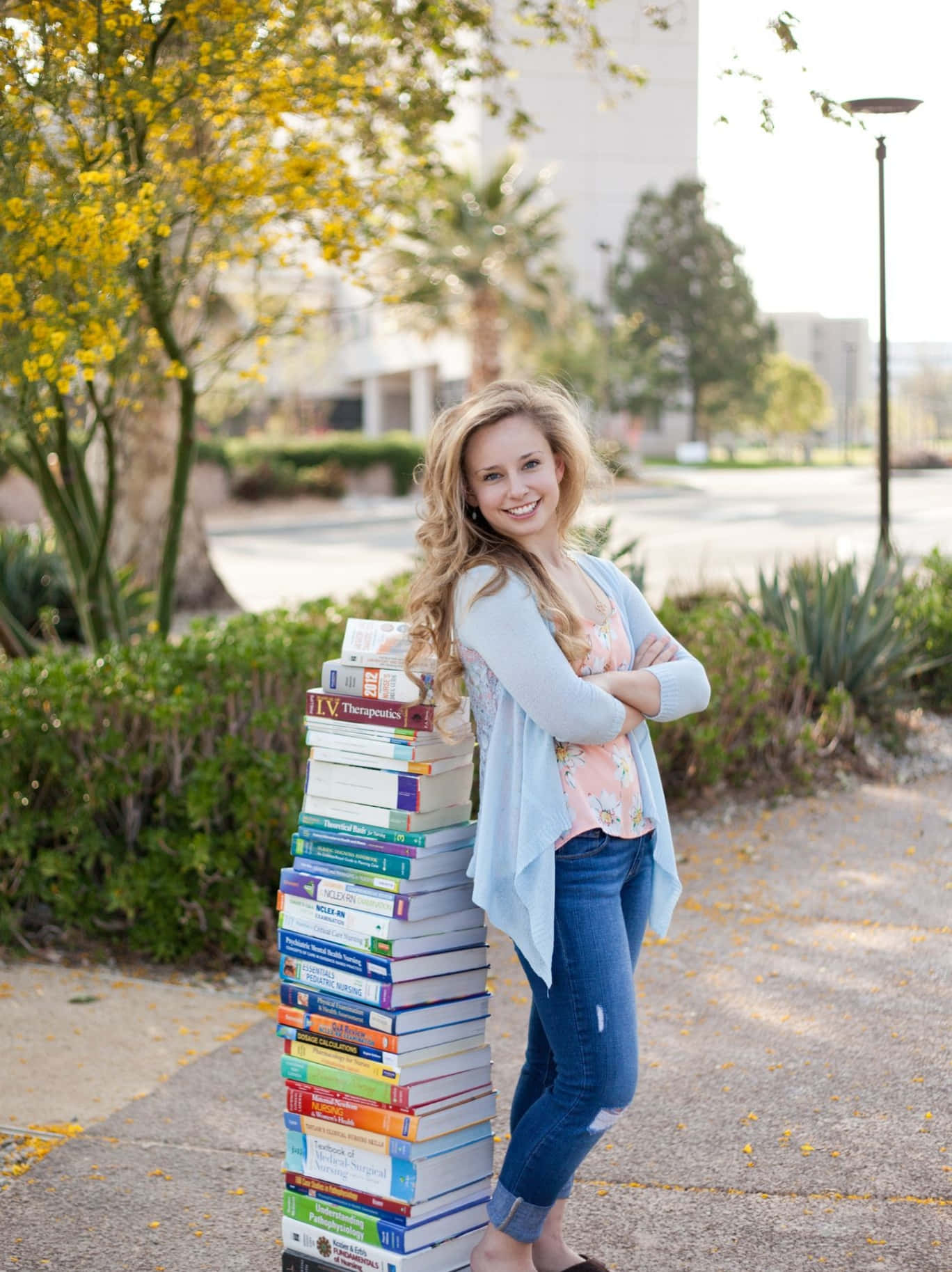 A Young Woman Standing Next To A Stack Of Books