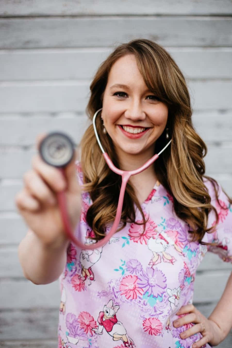 A Woman In A Pink Scrub Top Holding A Stethoscope