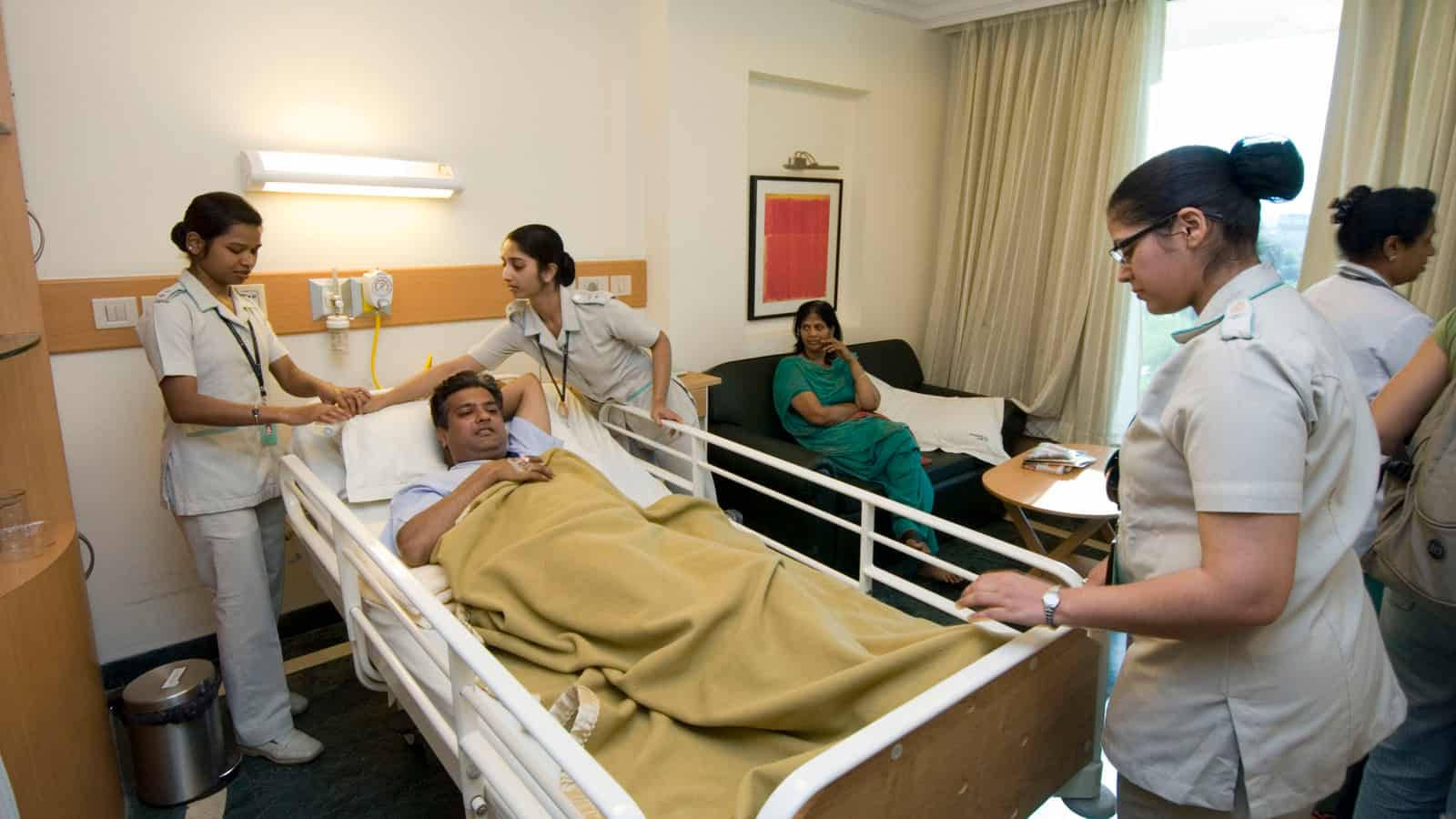 Plejemedicinskteam tager sig af patient ved sengen Wallpaper