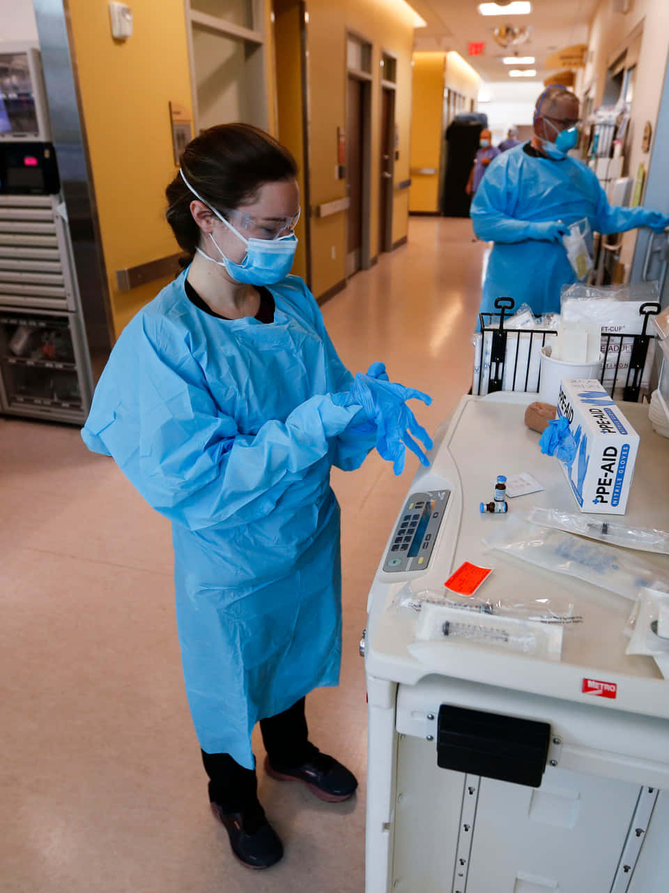 Tvåsjuksköterskor I Skyddsutrustning Står I En Sjukhuskorridor