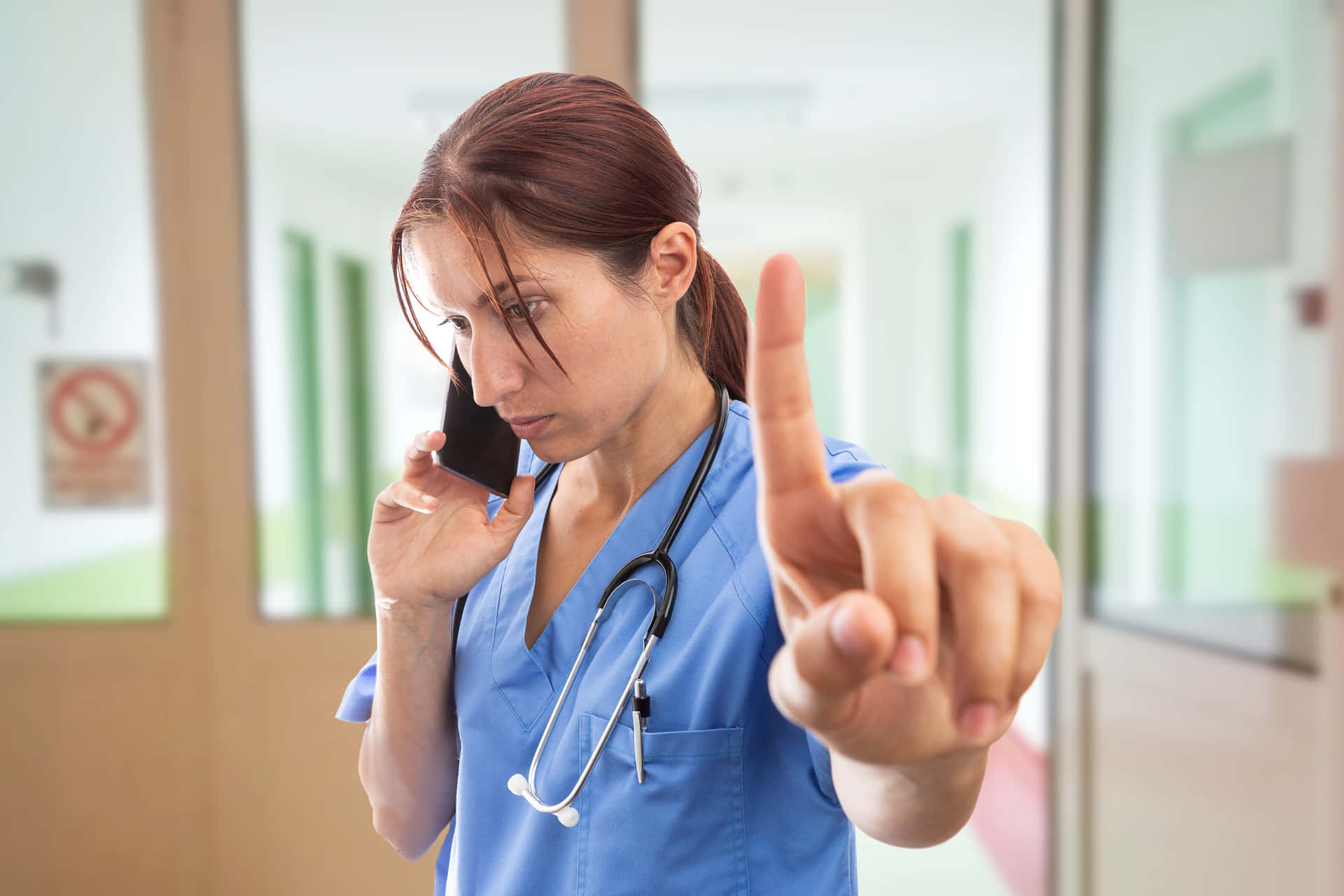 A Nurse Is Talking On The Phone While Pointing At Something