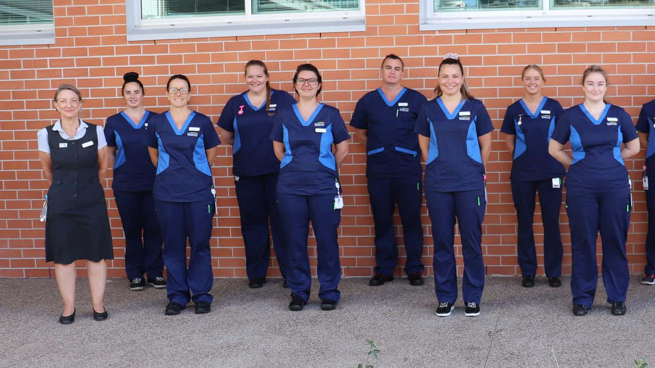 A Group Of Nurses Standing In Front Of A Brick Wall