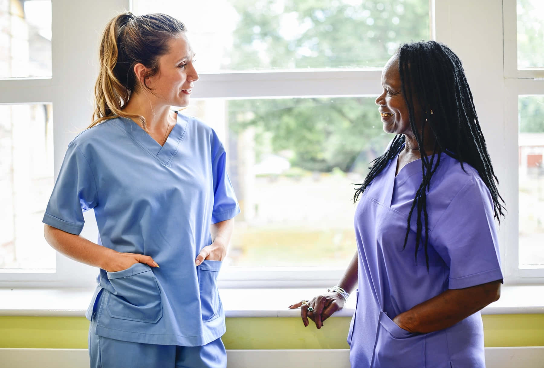 Two Nurses Talking In Front Of A Window