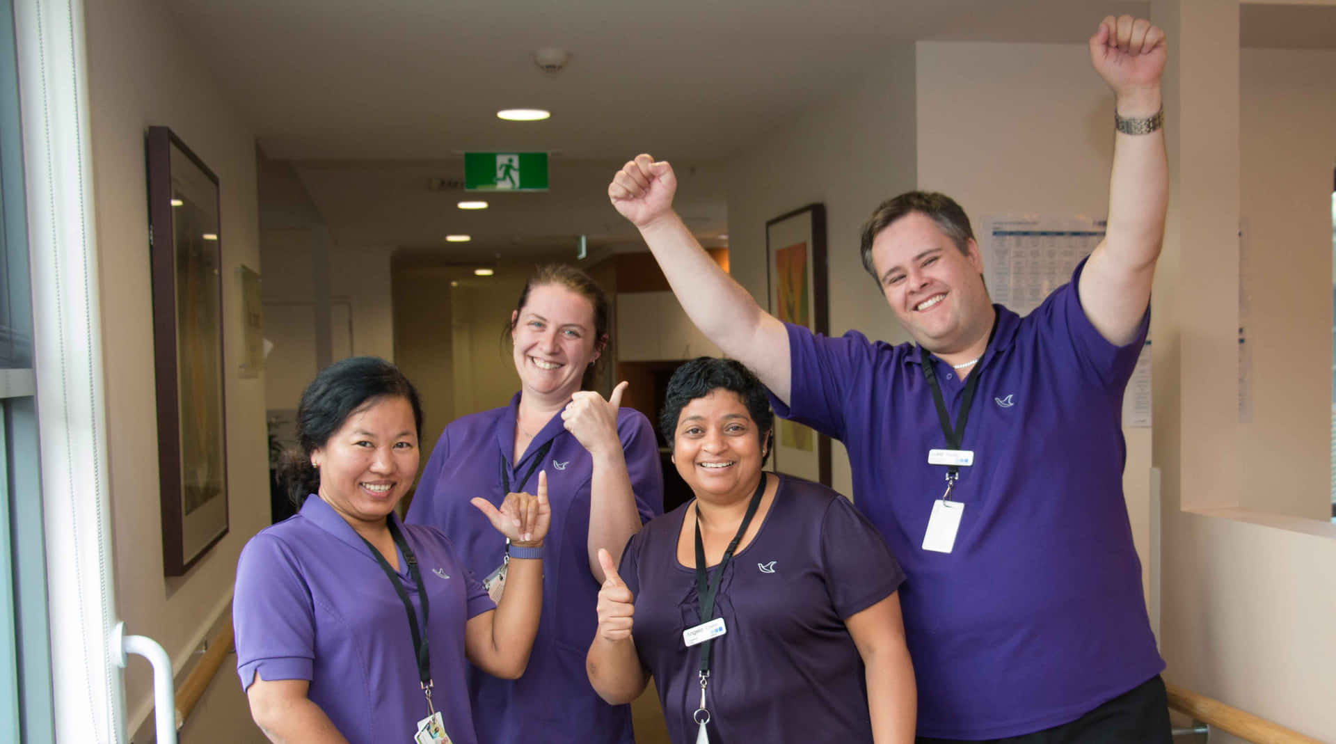 Four Nurses In Purple Shirts Standing In A Hallway