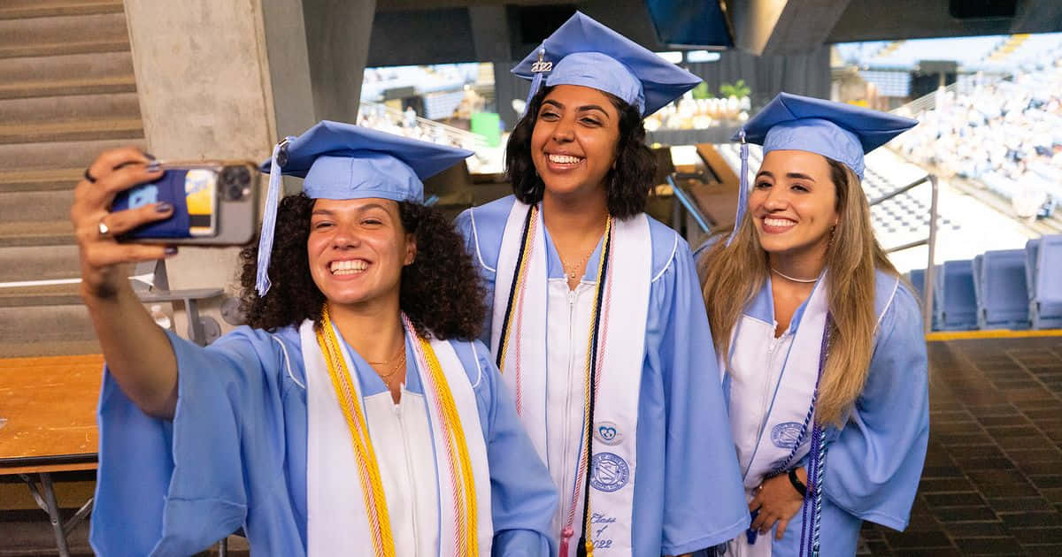 Three Women In Graduation Gowns Taking A Selfie