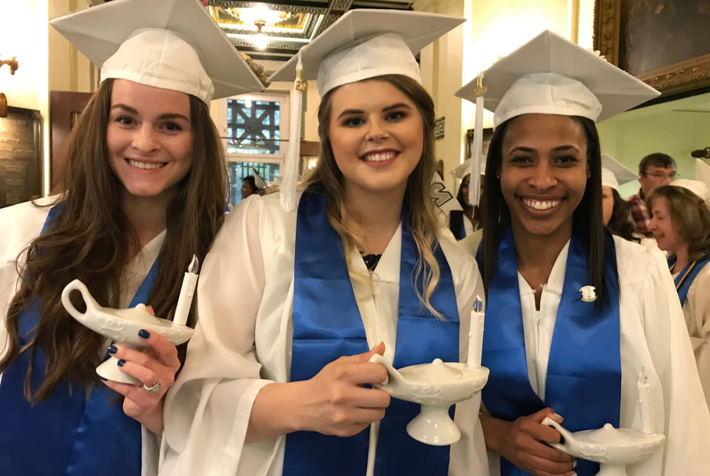 Three Women In Graduation Gowns Holding Cups
