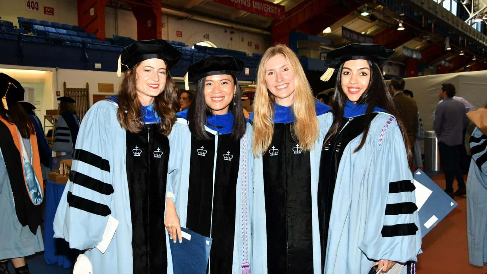 Four Women In Graduation Gowns Posing For A Photo