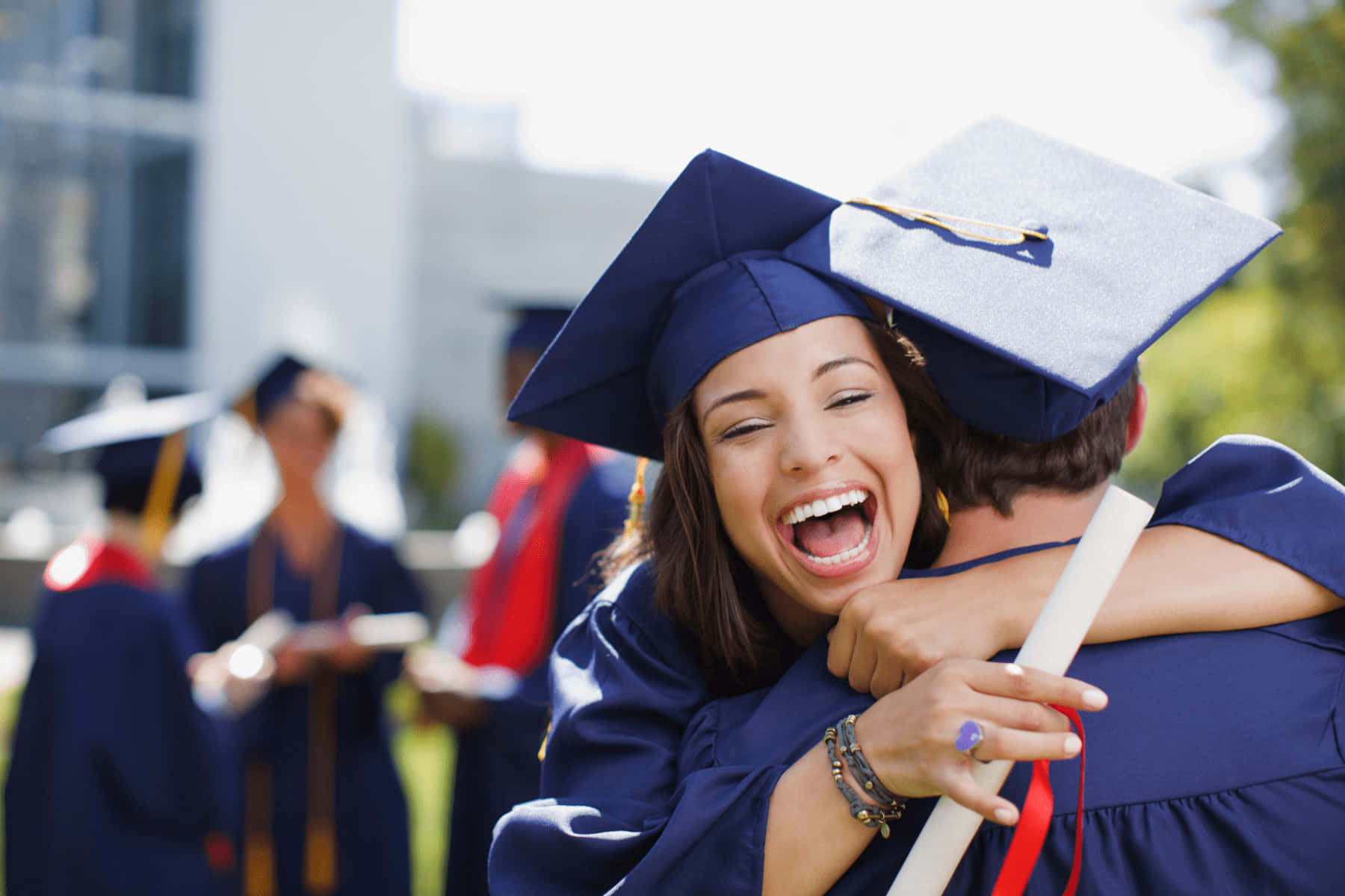 A Woman In Graduation Gown Hugging Another Woman