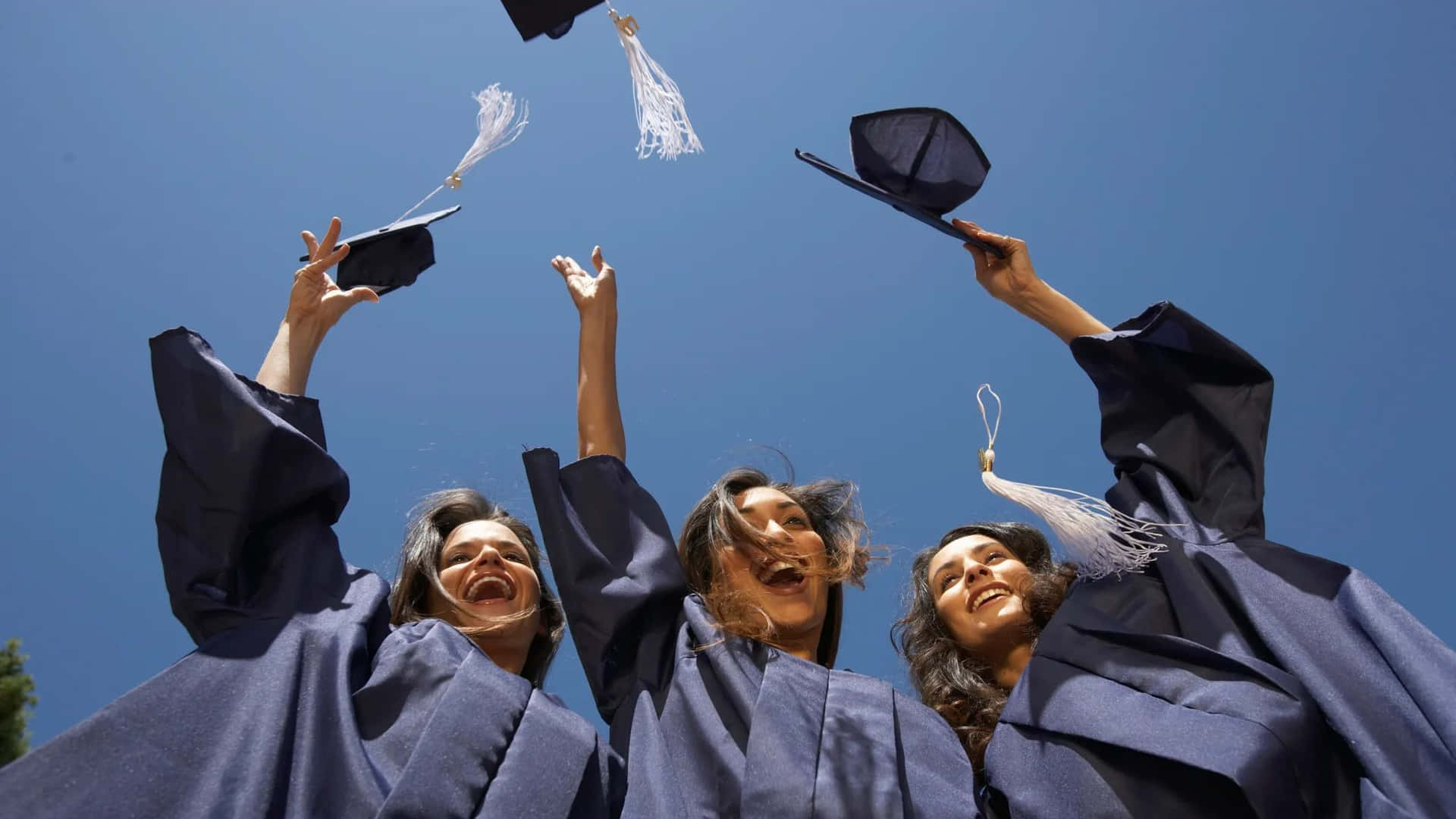 Three Graduates Tossing Their Caps In The Air