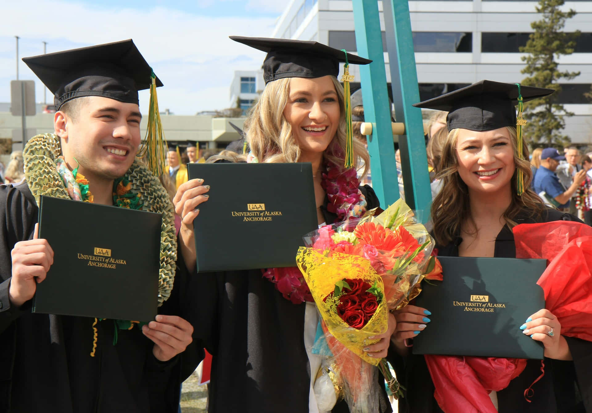 Four Graduates Holding Their Diplomas
