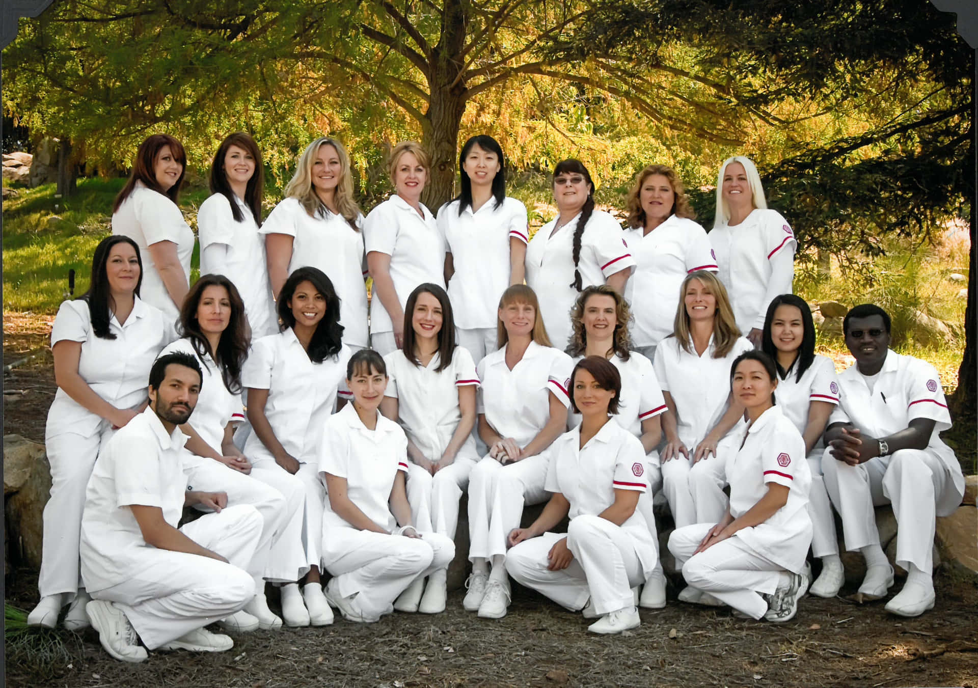 A Group Of Women In White Scrubs Posing For A Photo