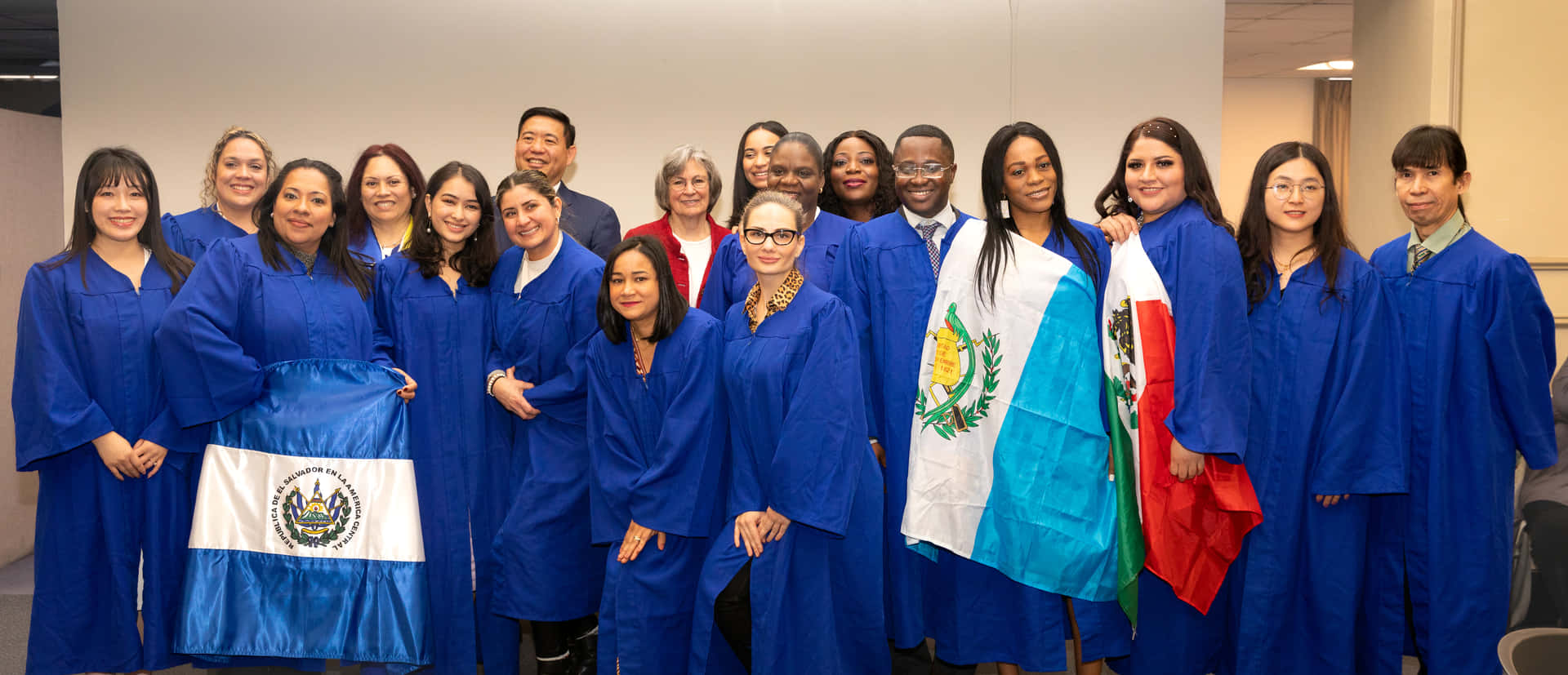 A Group Of People In Blue Graduation Gowns Posing For A Photo
