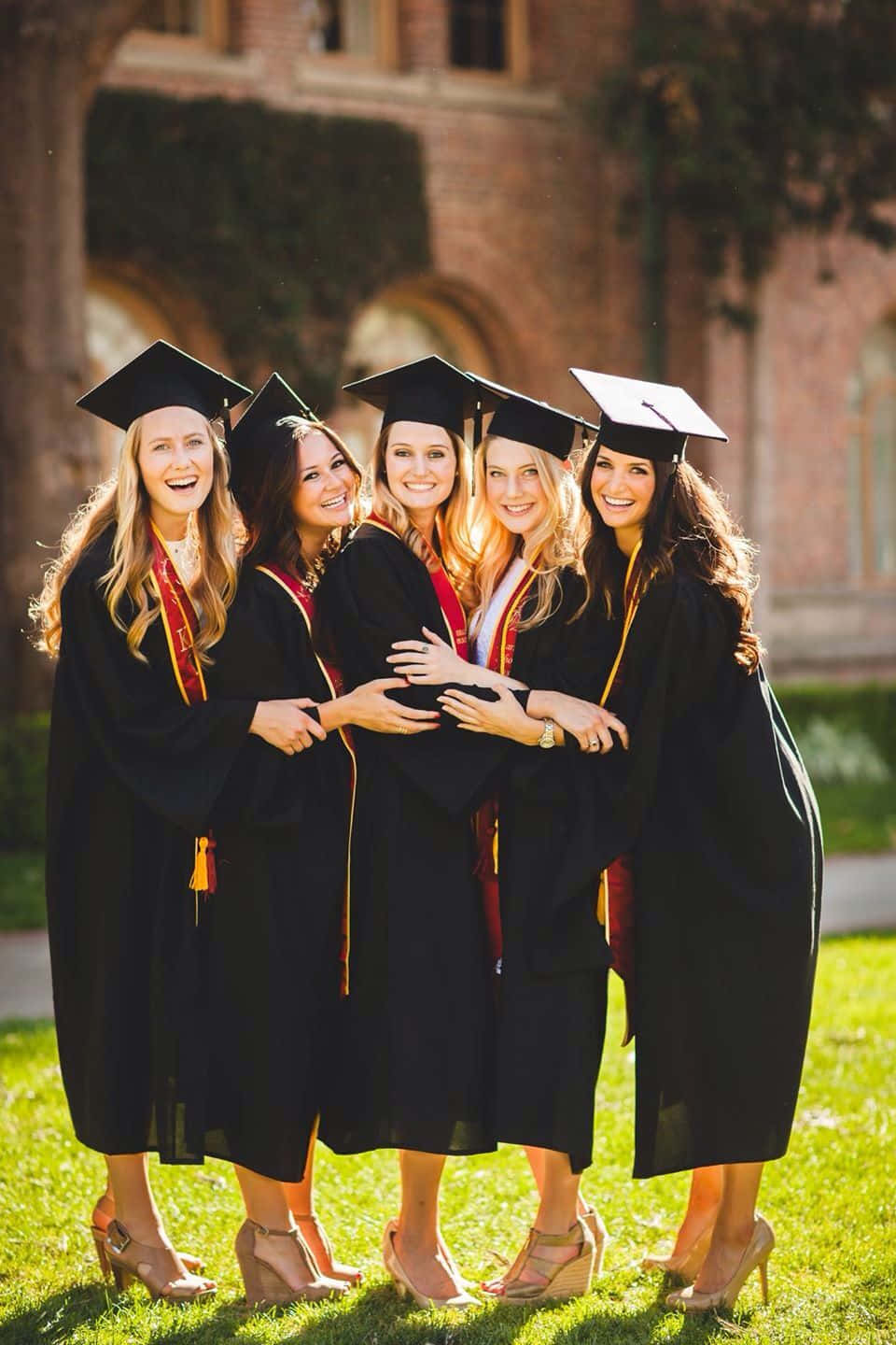 A Group Of Women In Graduation Gowns Hugging