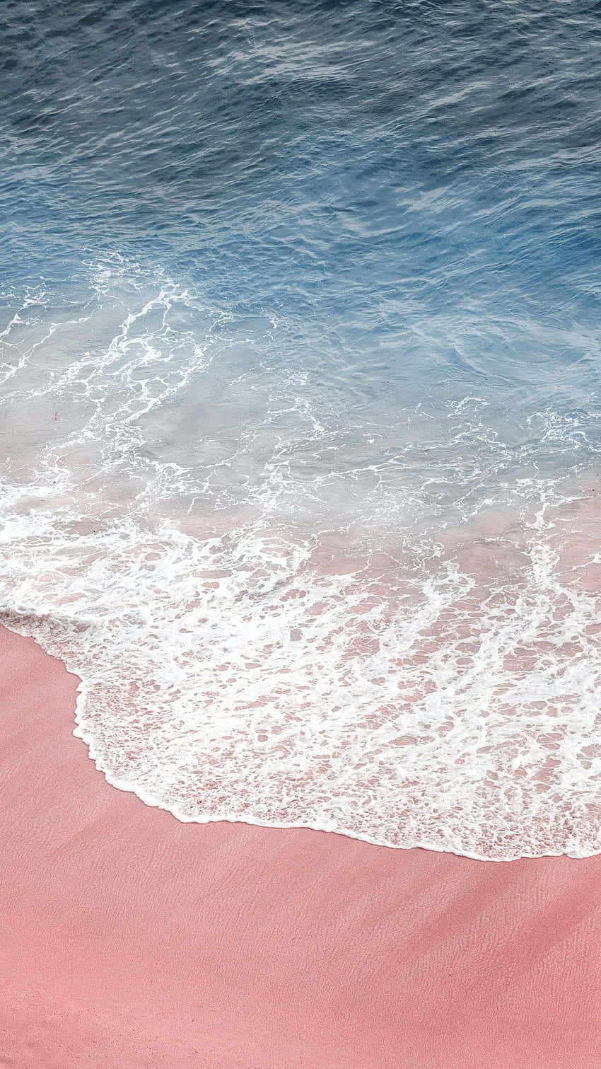 A Pink Sand Beach With Waves Wallpaper