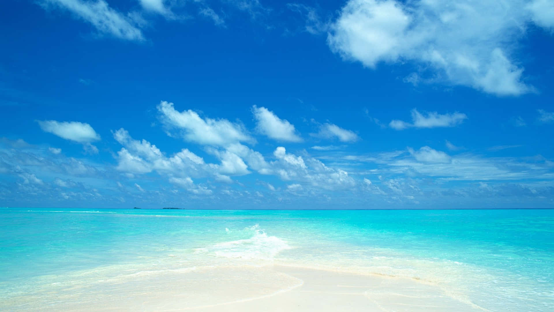 A Beach With Clear Water And Blue Sky Wallpaper