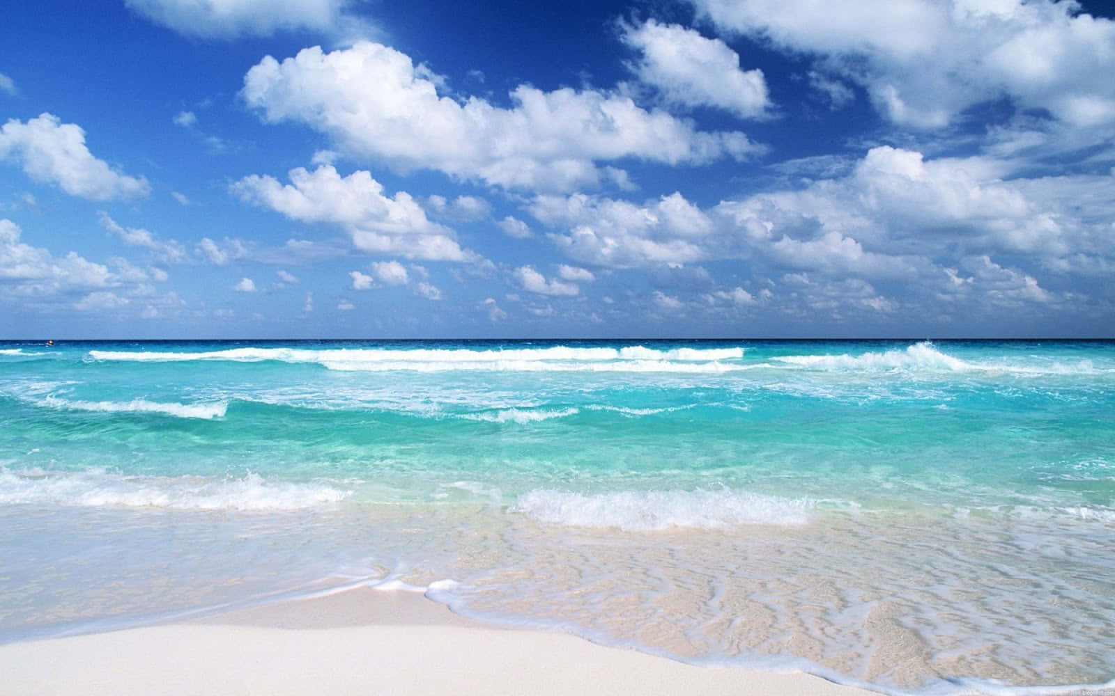 A Beach With Blue Water And White Clouds Wallpaper