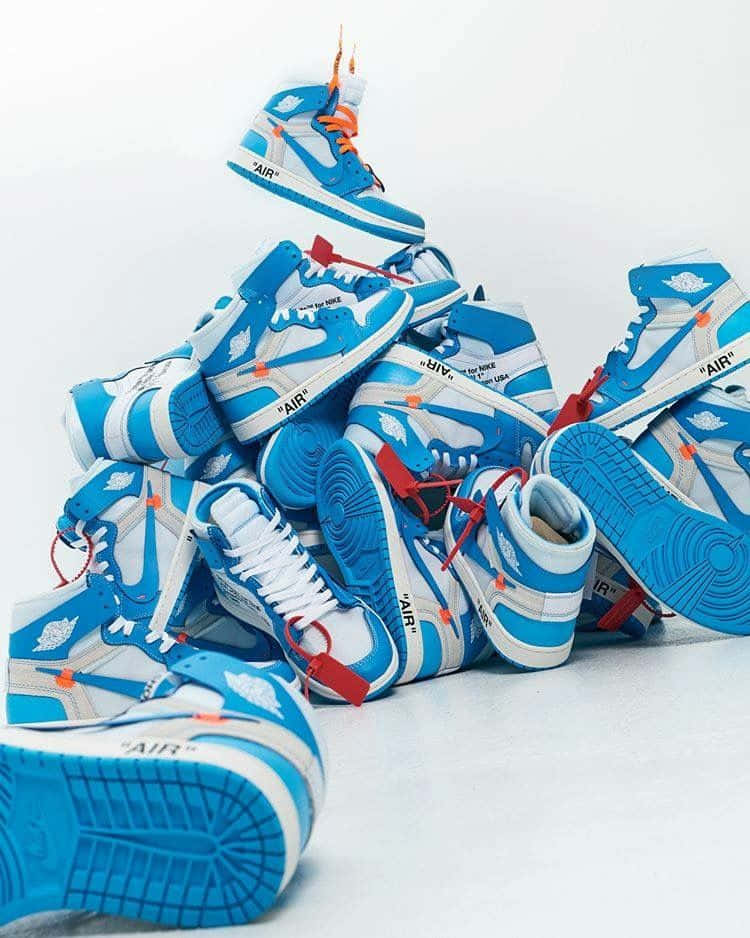 En bunke af blå og orange sneakers på en hvid overflade Wallpaper