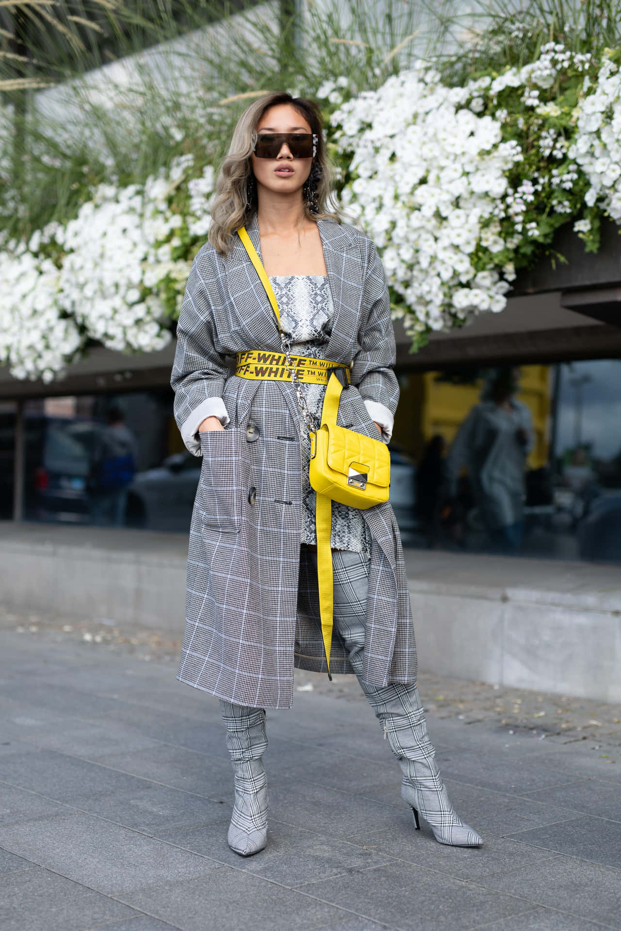 En kvinde i grå frakke og gul taske.