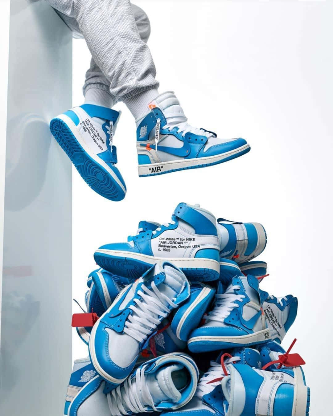 A Person Is Sitting On Top Of A Pile Of Blue And White Sneakers Wallpaper
