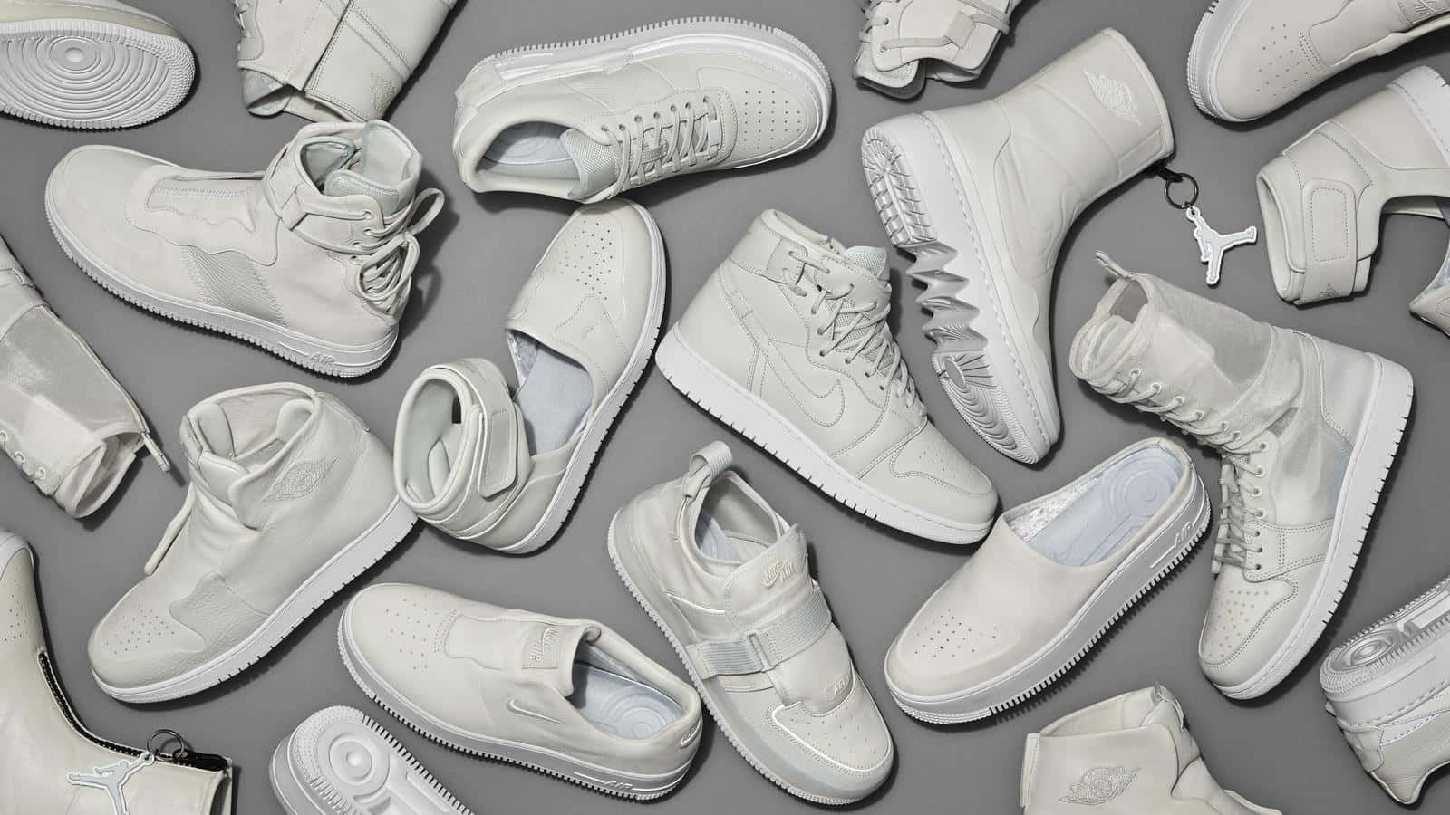 A Group Of White Sneakers Arranged On A Grey Background Wallpaper