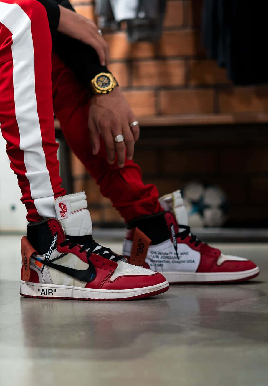 A Man Is Sitting On A Red And White Air Jordan 1 Wallpaper