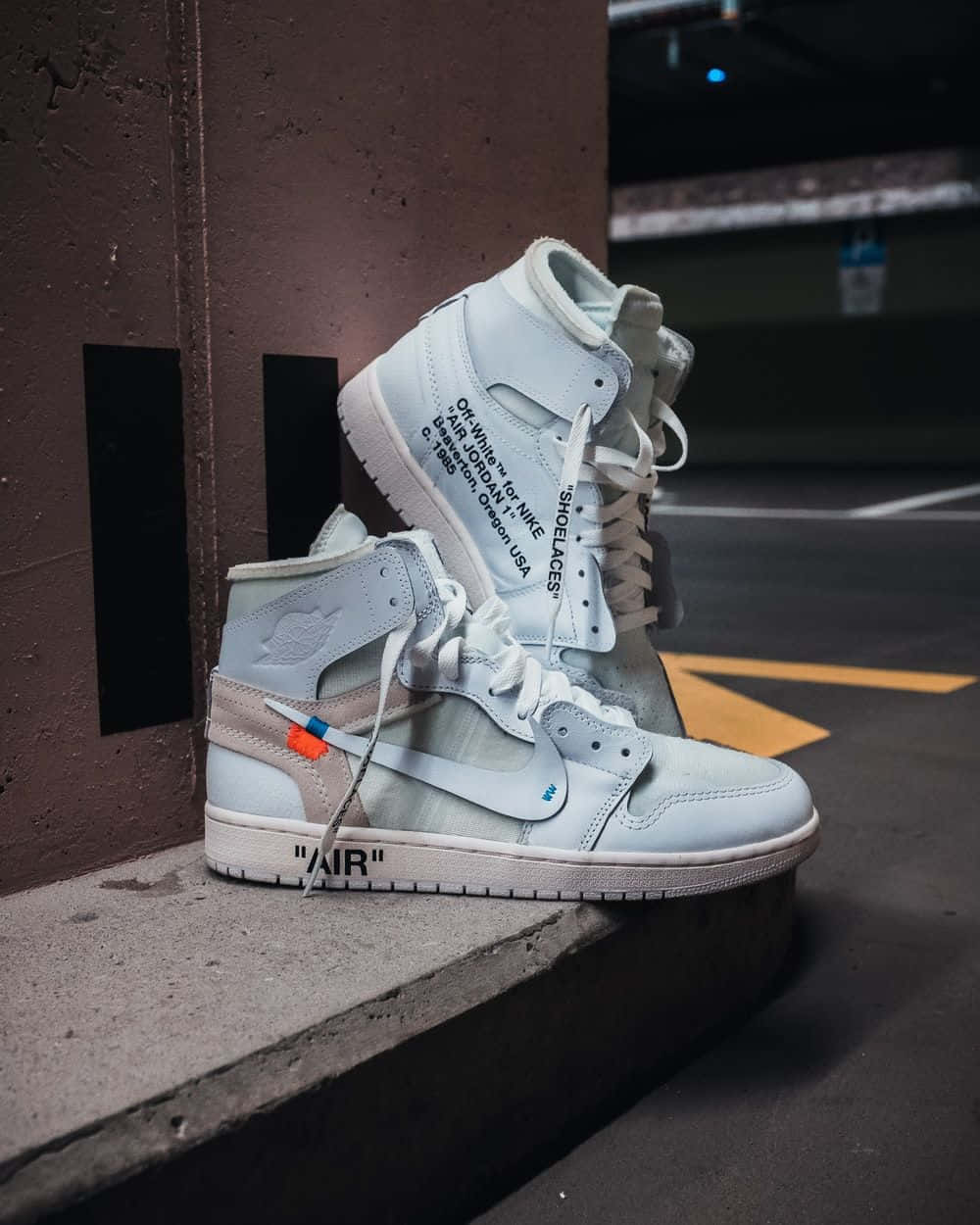 A Pair Of White Air Jordan 1 High Sneakers Sitting On A Concrete Wall Wallpaper