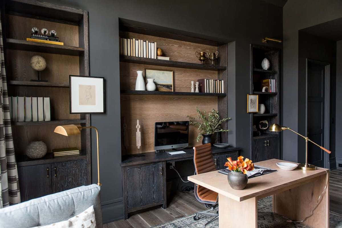 A Home Office With Dark Wood Walls And A Desk